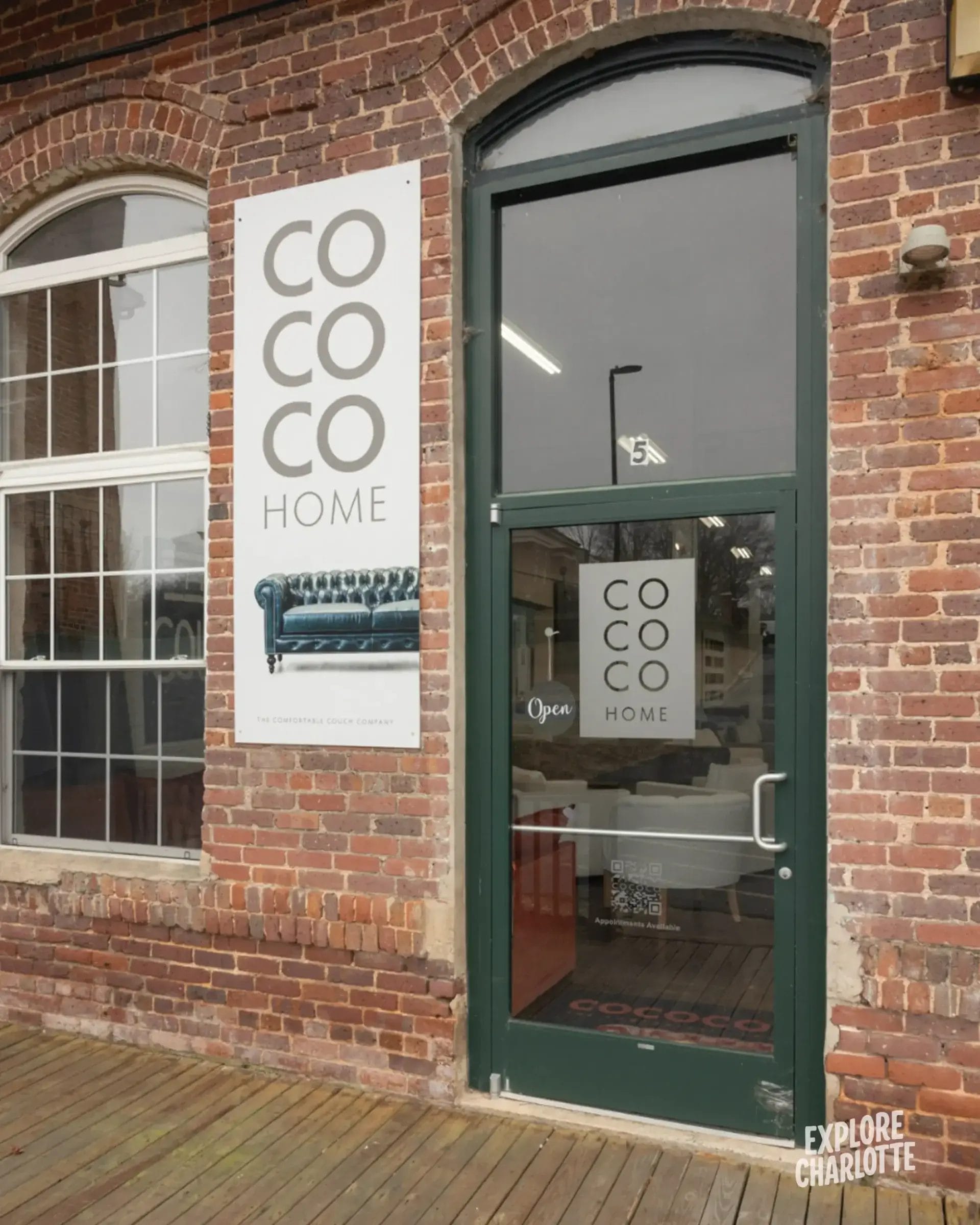 A brick shopfront in Cornelius, NC features a green-framed door, "COCO HOME" signs, and a window showing local furniture.
